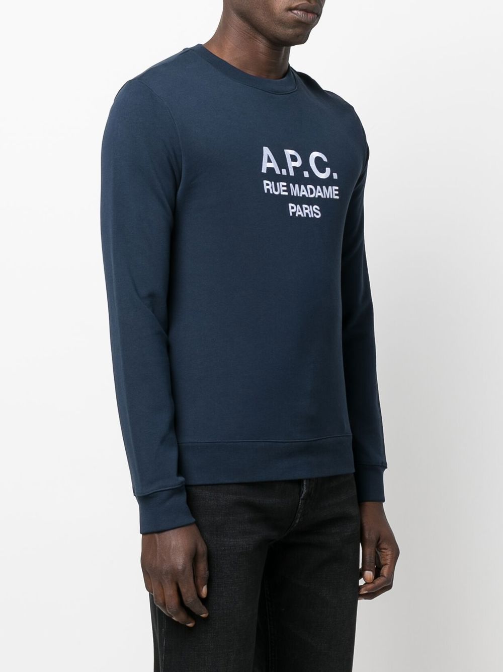 Person wearing a navy blue sweatshirt with 'A.P.C.' branding on a white background