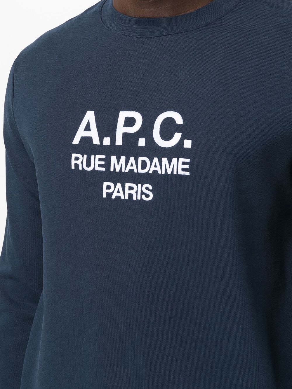 Person wearing a navy blue sweatshirt with 'A.P.C.' branding on a white background